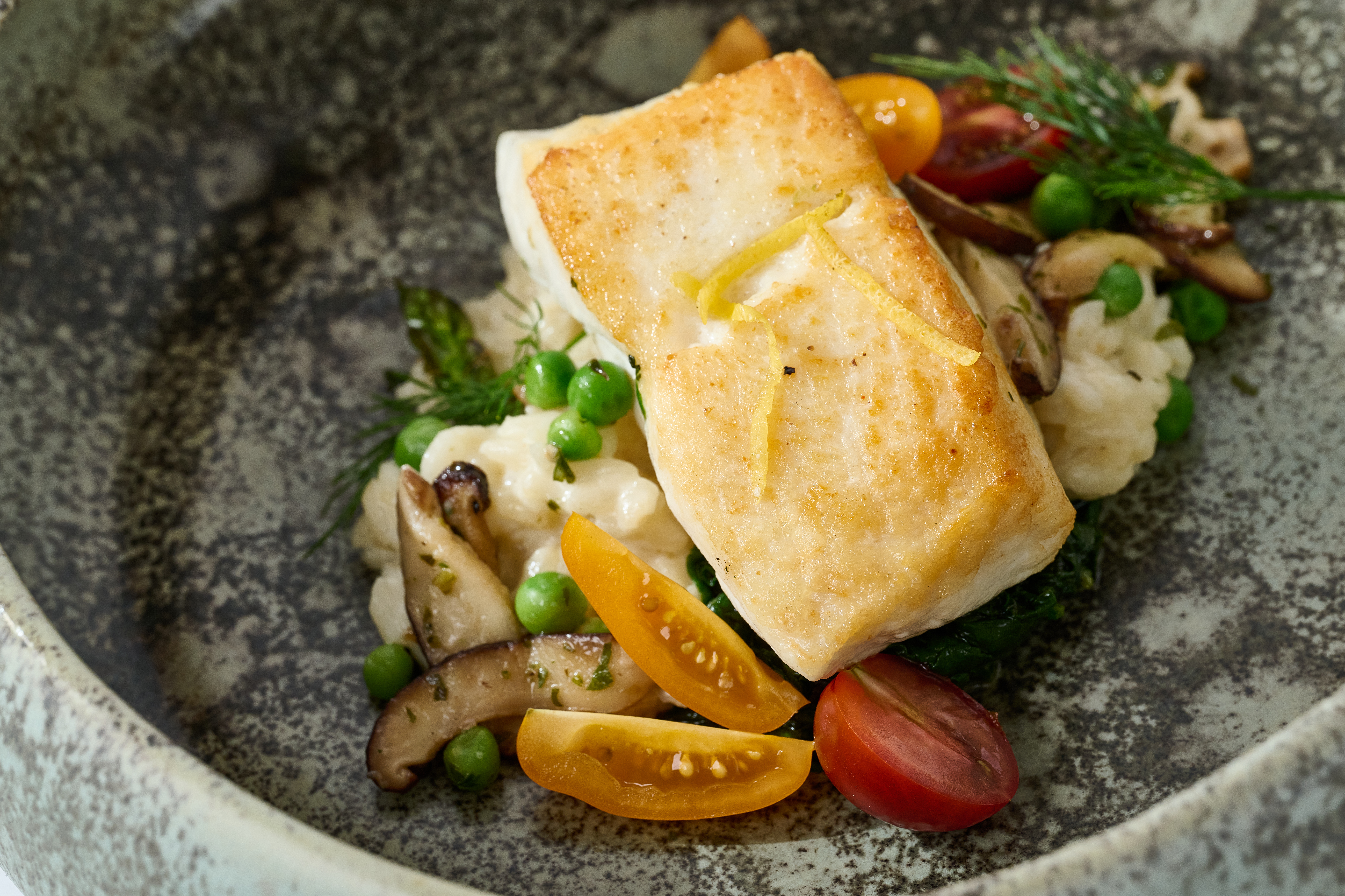 A plated dish of fish, risotto, and vegetables