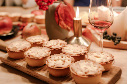 8 mini pies lined up by a glass of wine
